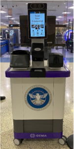 CAT 2 scanner at an airport security checkpoint. At the top middle of the scanner is a screen stating "Scan Your Credential." The base of the scanner has the Transportation Security Administration crest, and the brand name Idemia is posted on the device.