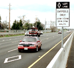 Cars driving on the freeway next to a carpool lane sign.